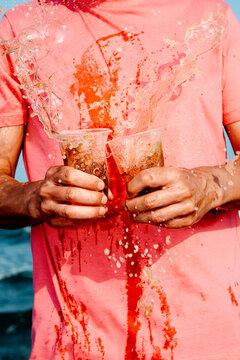 beer splash as man in pink shirt fumbles cups on the beach
