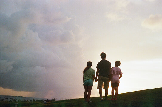 Family Silhouette Watching Sunset on Hilltop
