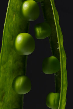 Green peas inside a fresh pod on a dark background