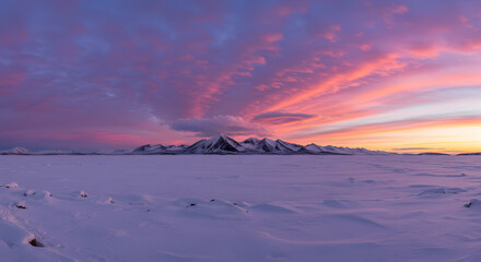 Spectacular Winter Sunset over Snow-Covered Plain and Distant Mountains with Vibrant Sky
