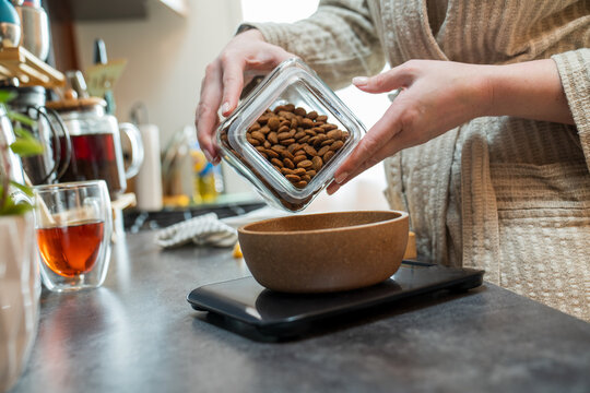 Close-up of pouring dog kibble into bowl on kitchen scale
