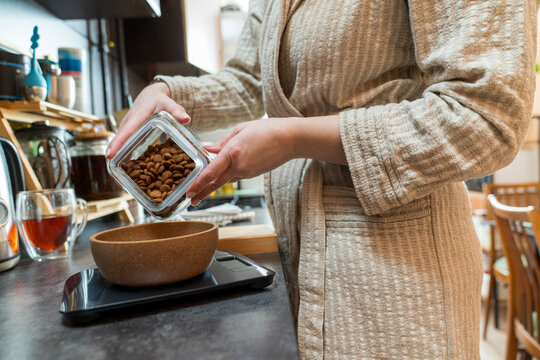 Close-up of pouring dog kibble into bowl on kitchen scale