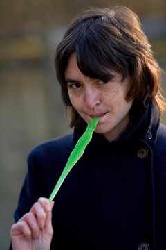 Young Person Holding Green Candy While Outdoors in Autumn Light