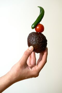 Hand Holding Unique Vegetable Stack With Tomato, Avocado, and Pepper