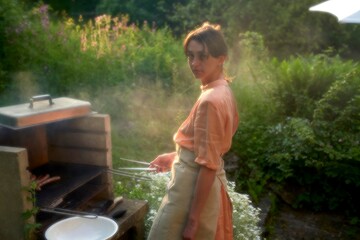 Woman Grilling Outdoors in a Lush Garden During Summer Evening