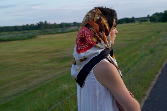Young Woman Gazing at a Lush Field During Sunset in Summer