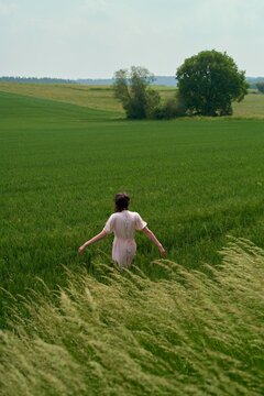 Young Woman Walks Through a Lush Green Field on a Sunny Day