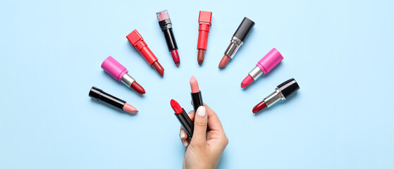 Female hand holding lipsticks on blue background