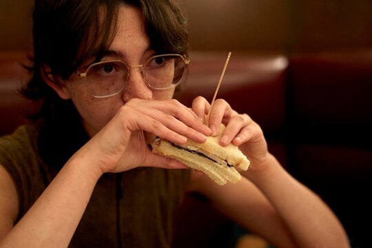 Person Enjoying a Sandwich in a Cozy Restaurant Setting