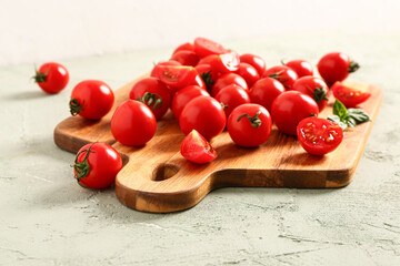 Wooden board with fresh cherry tomatoes on grey table