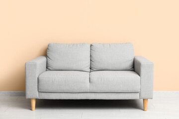 Cozy grey sofa near beige wall