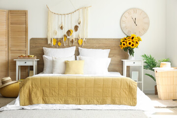 Interior of light bedroom with sunflowers in vase on table