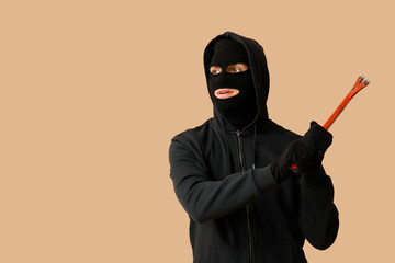 Male thief with crowbar on beige background