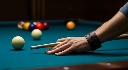 A man is playing pool with a group of balls on the table. He is holding a pool stick and is about to hit one of the balls