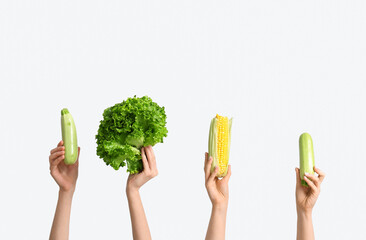 Female hands holding fresh vegetables on white background