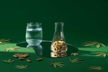 The image showcases capsules, water, and cannabis elements on green