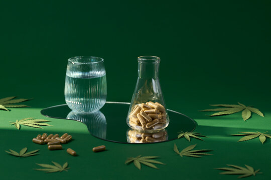 The image showcases capsules, water, and cannabis elements on green