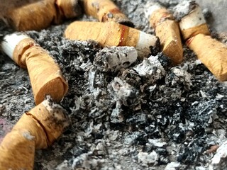Close-up of a cigarette butt and ash pile, representing smoking and addiction