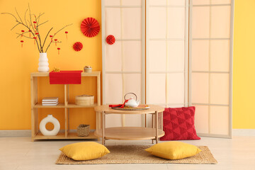 Interior of living room decorated for Chinese New Year with table, shelf unit and folding screen