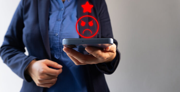 Low rating on satisfaction evaluation. People holding a cell phone with an angry person icon with only one star.