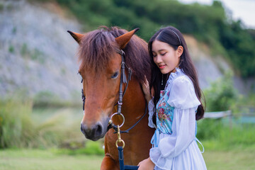 Young woman in floral dress gently interacts with brown horse in serene outdoor setting