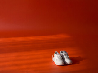 White sneakers on a vibrant orange backdrop
