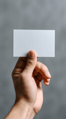 Closeup of a Person's Hand Holding a Blank White Card Against a Gray Background