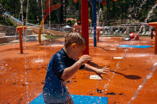Child enjoys water play at splash pad during summer afternoon