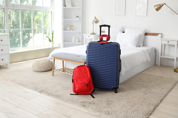 Bags with headphones and passport on carpet in hotel room interior