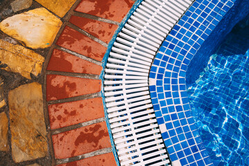 Poolside view showcasing vibrant tiles and textured stone path