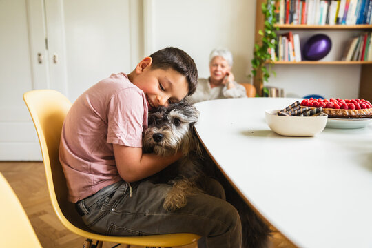 Boy Affectionately Hugging Dog at a Table