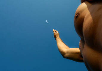 Man Reaching for the Crescent Moon in a Clear Blue Sky