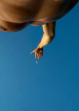 Reaching Towards the Crescent Moon Against a Clear Blue Sky