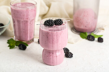Glasses of fresh blackberry smoothie with mint and berries on white background