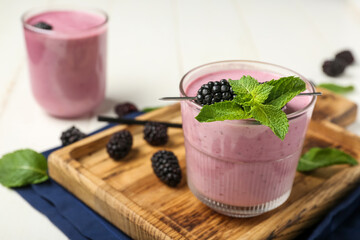 Glasses of fresh blackberry smoothie with mint on white wooden background, closeup