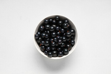 Bowl with fresh black currants on white background