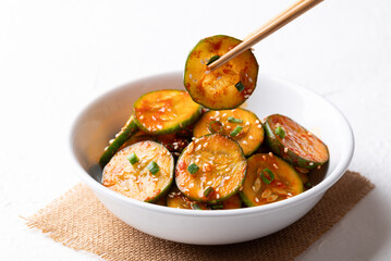 Korean cucumber salad (Oi muchim) in bowl with chopsticks on white background, Korean side dish © nungning20