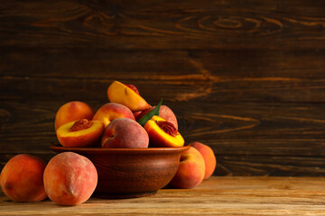 Bowl with sweet ripe peaches on wooden background