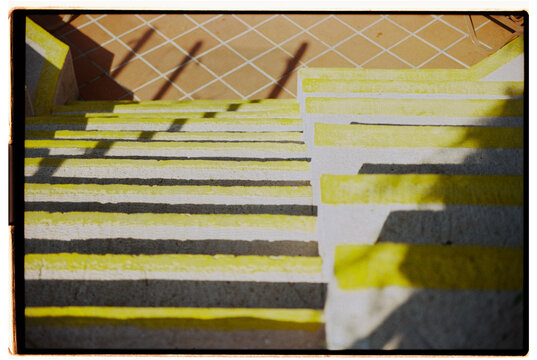Staircase with yellow stripes leading downward on sunny day