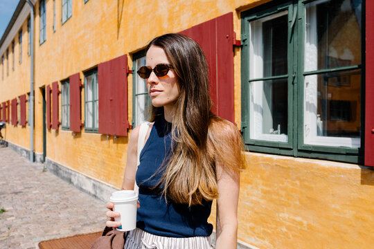 Tourist strolling in Nyboder in Copenhagen with a takeaway coffee