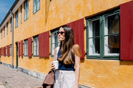Tourist walking through the streets of Nyboder with a takeaway coffee