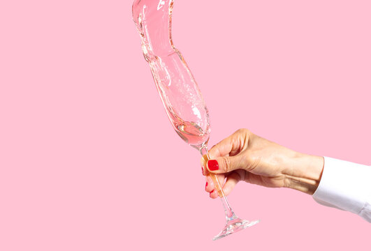 Oops! Woman Holding Splashing Flute of Pink Champagne. 