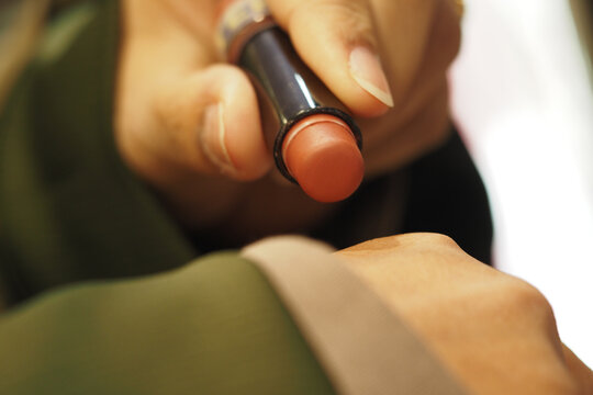Person applying lipstick in a beauty store