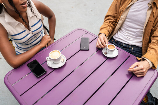 Colleagues enjoying coffee break and talking at purple table