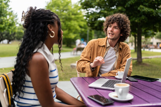 University students discussing project at outdoor cafe table