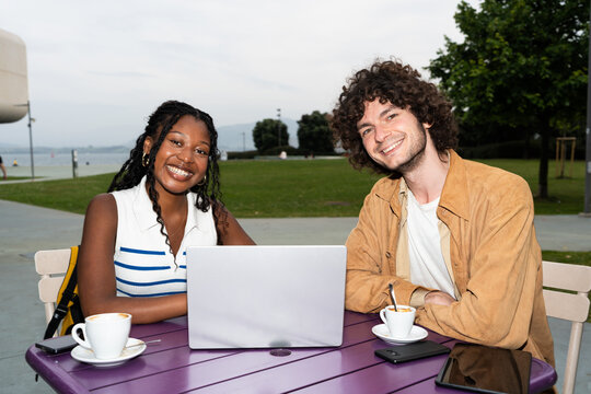 Students working on laptop and drinking coffee at outdoor table
