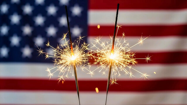 Two glowing sparklers celebrating American pride and freedom with the USA flag blurred in the background for a festive national holiday.