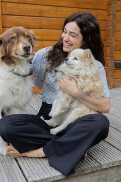 woman cuddling with two dogs