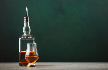 15 year old whiskey single malt scotch whisky in glencairn glass with bottle on dark green...
