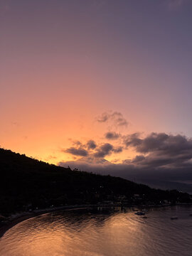Fiery sunset over bay and volcano silhouette